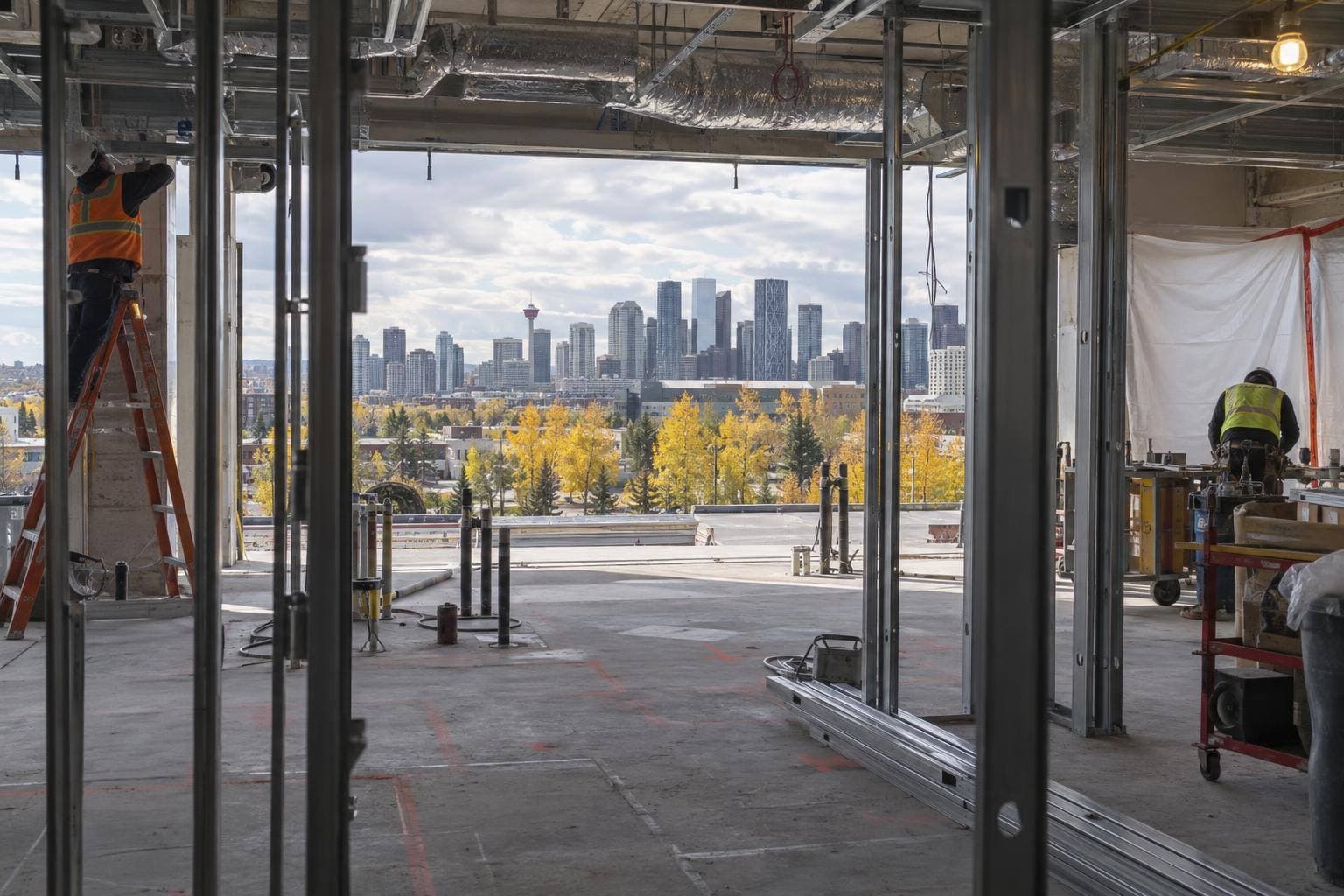 A gutted office floor plate with partitions removed, exposed steel studs and mechanical, electrical and plumbing rough-ins being installed by crews.